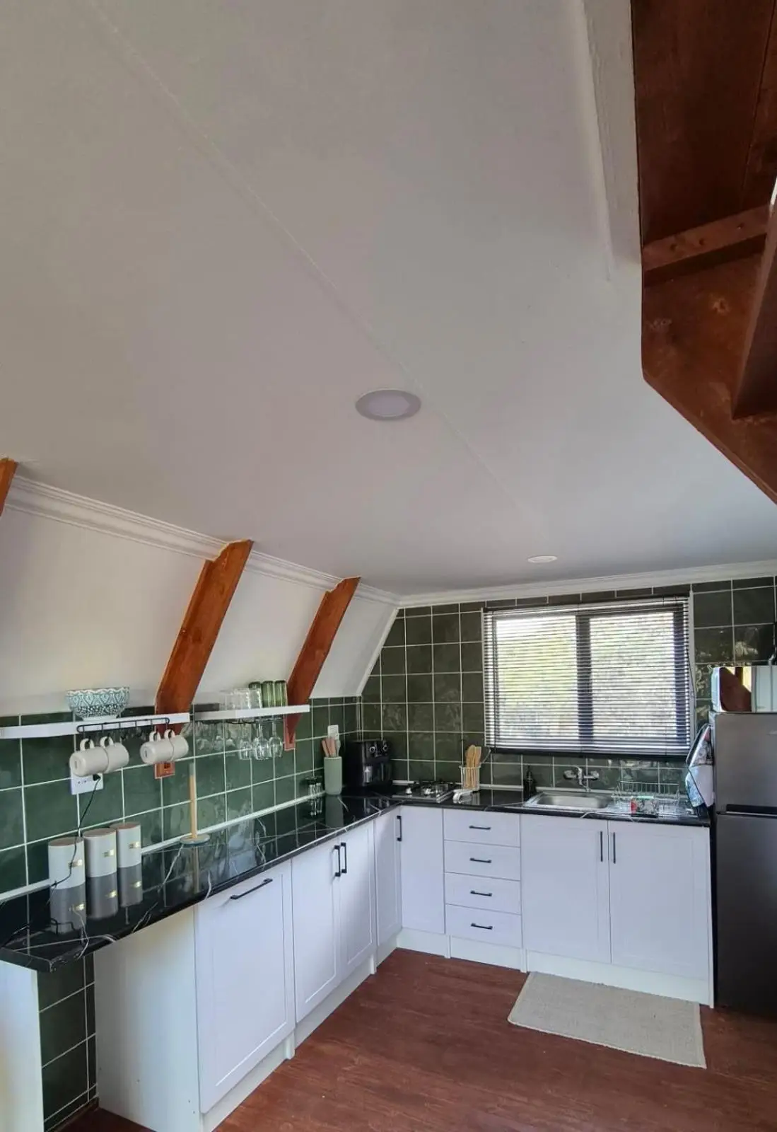 The kitchen, with dark green tiles and white cupboards