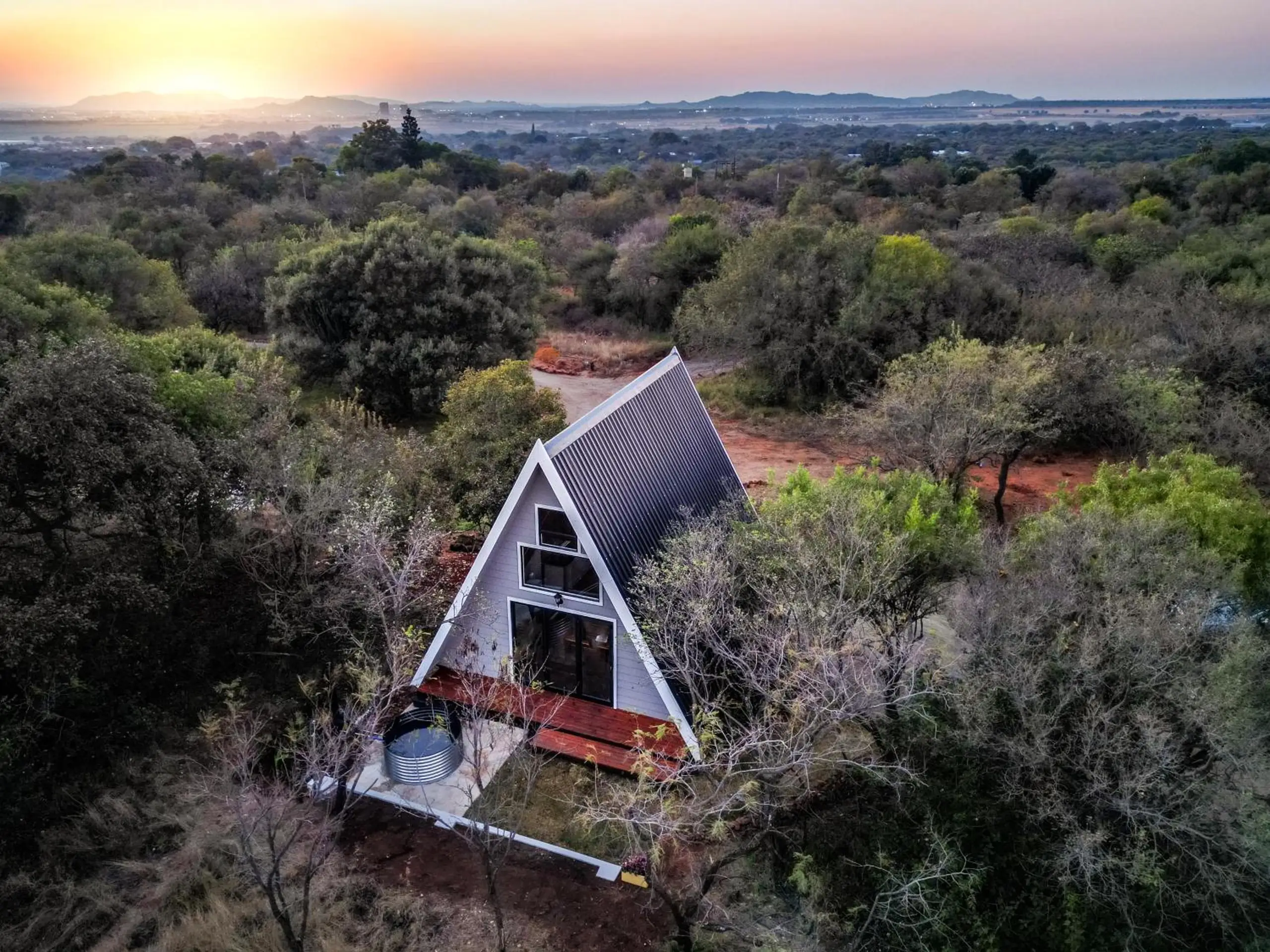 From above: a cabin among the thorn trees, the red earth paths and the hills beyond
