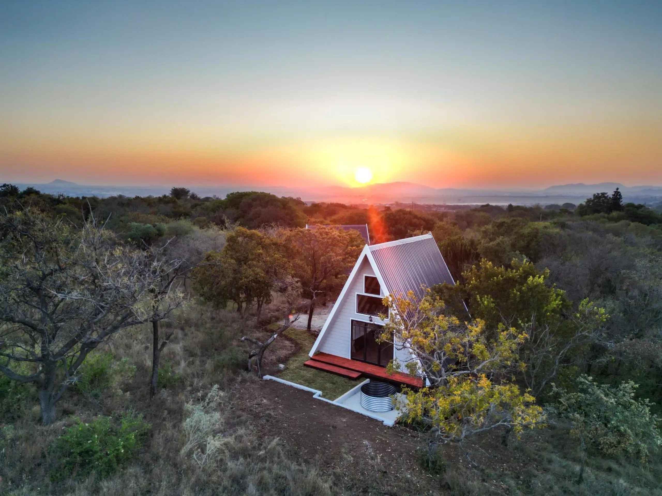A Scheepers Nest A-frame among the thorn trees at sunset, the Magaliesberg on the horizon