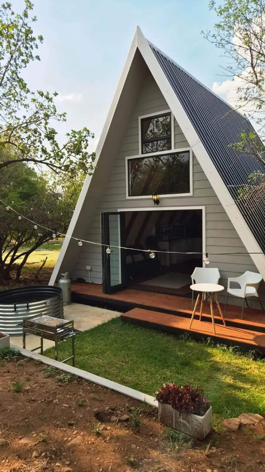 The cabin's gable: glass doors onto a timber deck, festoon lights and the tank pool